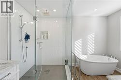 Full bathroom with a marble finish shower, a freestanding tub, vanity, and recessed lighting - 
