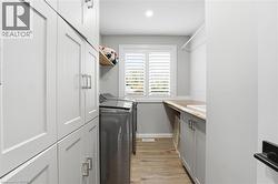 Laundry room with light wood-style flooring, separate washer and dryer, and cabinet space - 