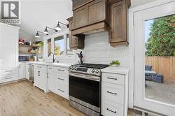 Kitchen featuring stainless steel appliances, light countertops, backsplash, vaulted ceiling, and light wood-type flooring - 