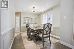 Dining space with wood finished floors, wainscoting, a textured ceiling, and a decorative wall - 