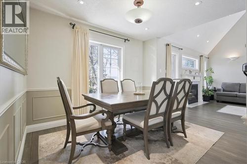 Dining room with a fireplace with flush hearth, dark wood-style flooring, lofted ceiling, a decorative wall, and wainscoting - 629 Burning Bush Road, Waterloo, ON - Indoor Photo Showing Dining Room