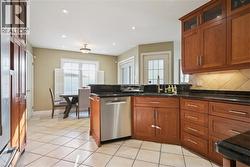 Kitchen featuring brown cabinetry, stainless steel dishwasher, a peninsula, fridge, and recessed lighting - 