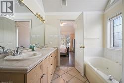 Full bathroom featuring double vanity, a whirlpool tub, connected bathroom, light tile patterned floors, and ornamental molding - 