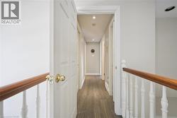 Hallway featuring dark wood-style floors, an upstairs landing, and recessed lighting - 
