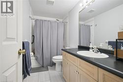 Bathroom featuring vanity, shower / tub combo with curtain, and light tile patterned floors - 