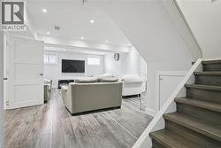 Living room with stairs, light wood finished floors, and recessed lighting - 