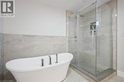 Bathroom with a freestanding bath, tile walls, a stall shower, and wainscoting - 