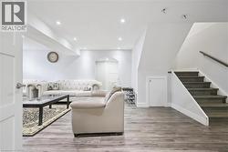 Living area with arched walkways, recessed lighting, light wood-style flooring, and stairway - 