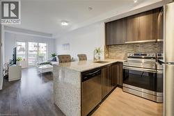 Kitchen with light stone counters, decorative backsplash, a peninsula, and dark brown cabinets - 