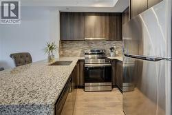 Kitchen featuring appliances with stainless steel finishes, dark brown cabinetry, light stone countertops, and decorative backsplash - 
