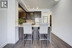 Kitchen with a peninsula, light stone countertops, dark brown cabinets, backsplash, and freestanding refrigerator - 