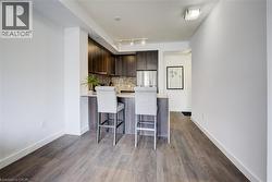 Kitchen with dark brown cabinetry, a peninsula, modern cabinets, light stone countertops, and backsplash - 