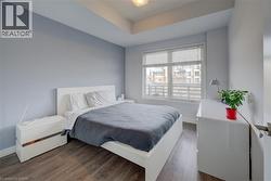 Bedroom featuring dark wood-style floors, recessed lighting, and a raised ceiling - 