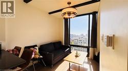 Living room featuring a skyline view, wood finished floors, beamed ceiling, and a chandelier - 
