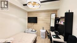Bedroom with light wood-style floors, an office area, and wood walls - 