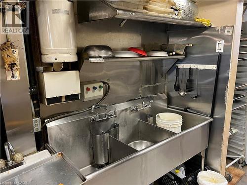Commercial-grade stainless steel triple sink with integrated faucet fixtures and upper shelving - 527 Upper Sherman Avenue, Hamilton, ON 