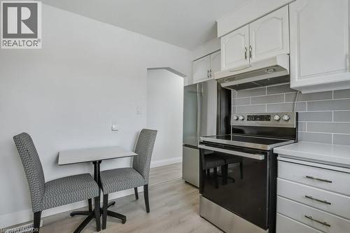 Kitchen featuring stainless steel appliances, under cabinet range hood, backsplash, white cabinetry, and light wood finished floors - 111 Castlefield Drive, Hamilton, ON - Indoor Photo Showing Kitchen