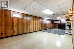 Below grade area with healthy amount of natural light, tile patterned floors, a drop ceiling, and wood walls - 
