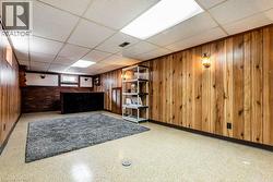 Below grade area with a drop ceiling, wooden walls, and tile patterned floors - 