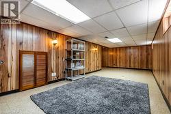 Finished below grade area featuring a drop ceiling and wood walls - 