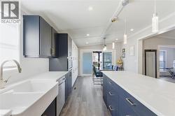 Kitchen with blue cabinetry, decorative light fixtures, healthy amount of natural light, dark wood finished floors, and vaulted ceiling - 
