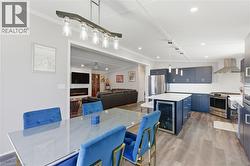Dining space with light wood-style floors, a lit fireplace, wine cooler, recessed lighting, and ceiling fan - 
