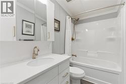 Bathroom featuring shower / bath combination with curtain, vanity, crown molding, and dark wood finished floors - 