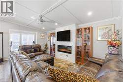 Living area featuring a fireplace, wood finished floors, ornamental molding, a ceiling fan, and recessed lighting - 