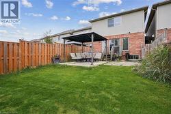 Rear view of property with a gazebo, a patio area, an outdoor hangout area, a fenced backyard, and brick siding - 