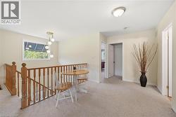 Hallway featuring light carpet and an upstairs landing - 