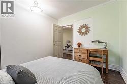 Bedroom featuring dark wood finished floors and ornamental molding - 