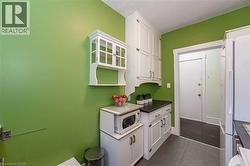 Kitchen with white appliances, dark tile patterned floors, white cabinets, and dark countertops - 