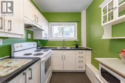 Kitchen with white appliances, under cabinet range hood, dark tile patterned floors, white cabinets, and glass insert cabinets - 