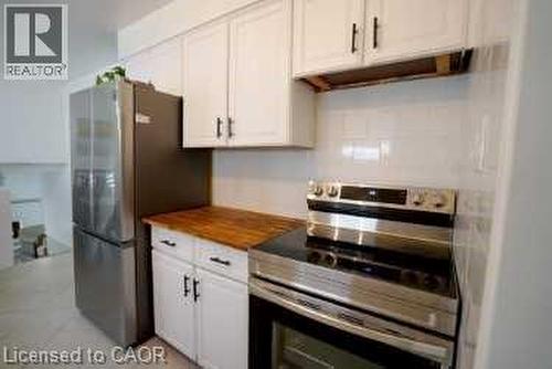 Kitchen featuring stainless steel appliances, white cabinetry, wooden counters, and under cabinet range hood - 147 Muriel Crescent, London, ON - Indoor Photo Showing Kitchen