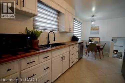 Kitchen featuring white cabinets, black microwave, light tile patterned flooring, hanging light fixtures, and dishwasher - 147 Muriel Crescent, London, ON - Indoor Photo Showing Kitchen