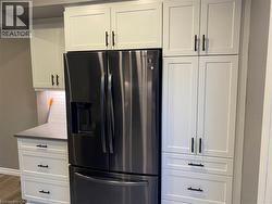 Kitchen with fridge with ice dispenser, white cabinets, tasteful backsplash, dark wood-style floors, and light countertops - 