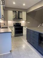 Kitchen featuring white cabinets, backsplash, black electric range oven, ventilation hood, and recessed lighting - 