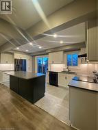 Kitchen featuring backsplash, white cabinetry, black range oven, stainless steel dishwasher, and fridge - 