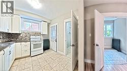 Kitchen featuring white cabinetry, white range with electric stovetop, dark countertops, and radiator - 