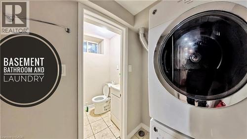 Laundry area featuring light tile patterned flooring and stacked washing machine and dryer - 25 Spadina Avenue, Hamilton, ON - Indoor Photo Showing Laundry Room