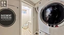 Laundry area featuring light tile patterned flooring and stacked washing machine and dryer - 
