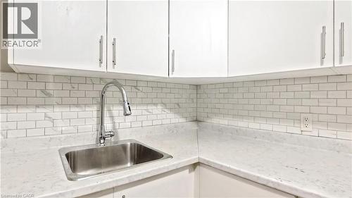 Kitchen view of white cabinets, tasteful backsplash, and light stone countertops - 25 Spadina Avenue, Hamilton, ON - Indoor Photo Showing Kitchen