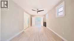 Empty room with a ceiling fan, light wood-style floors, and radiator - 