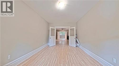 Hallway with baseboards and light wood-style floors - 25 Spadina Avenue, Hamilton, ON - Indoor Photo Showing Other Room