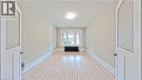 Corridor with light wood-style flooring and radiator - 25 Spadina Avenue, Hamilton, ON - Indoor Photo Showing Other Room