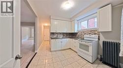 Kitchen with white electric range, radiator heating unit, white cabinets, and dark countertops - 