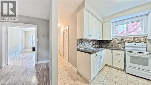 Kitchen featuring dark countertops, electric stove, white cabinetry, backsplash, and light wood-type flooring - 25 Spadina Avenue, Hamilton, ON - Indoor Photo Showing Kitchen