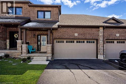 View of front of property with brick siding, a porch, a front yard, asphalt driveway, and a shingled roof - 24 Tamarack Way, Simcoe, ON - Outdoor