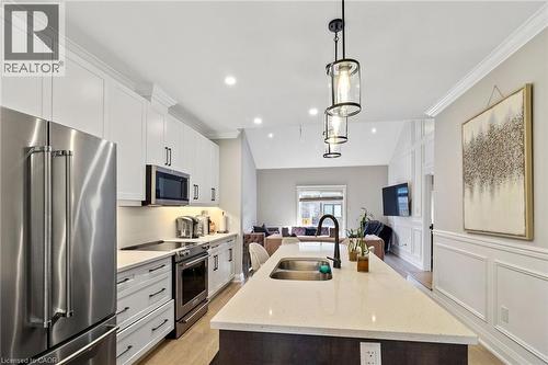 Kitchen featuring stainless steel appliances, light stone counters, open floor plan, decorative light fixtures, and a kitchen island with sink - 24 Tamarack Way, Simcoe, ON - Indoor Photo Showing Kitchen With Stainless Steel Kitchen With Double Sink With Upgraded Kitchen