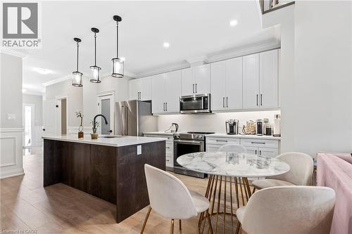 Kitchen with stainless steel appliances, a kitchen island with sink, a decorative wall, pendant lighting, and wainscoting - 24 Tamarack Way, Simcoe, ON - Indoor